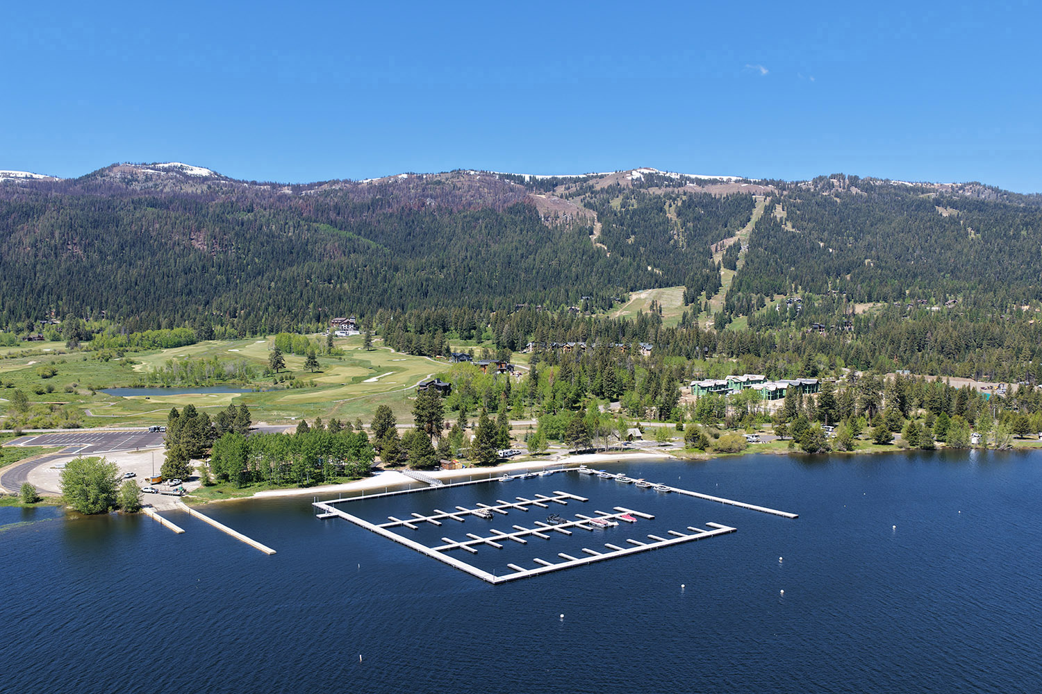 Aerial view of Tamarack Resort’s new Lake Cascade marina in Idaho, with docks, shoreline amenities, and forested mountain slopes in the background.